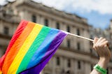A hand waving a rainbow pride flag.