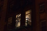 From the street, lights can be seen on in an apartment at night.