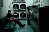 A person talking on the phone in a laundromat.