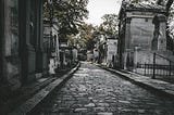 A darkish image of a cobblestone path to a graveyard.