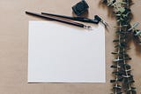 Fountain pen and blank piece of paper with eucalyptus leaves.