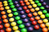 Neatly arranged lines of red, orange, yellow, green, and purple Skittles.