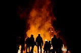 Photo of people standing around a fire by Alessio Soggetti on Unsplash
