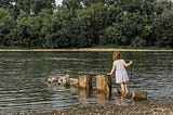 A young girl playing by the lake