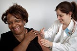 A healthcare professional administers a vaccine dose to a female patient.