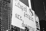 A protest holding a placard that reads: Stupid people are dangerous.