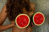 Woman holding up watermelons to her breasts