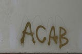 The letters “A C A B” spray-painted on a wall.