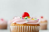 A cupcake with icing and a cherry on top