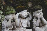3 stone statues of Buddha-like children. One covers their eyes; one, their ears; and one, their mouth.