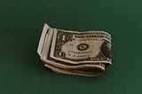 Stash of 1 dollar bills on dark green background