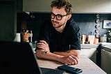 a man with glasses leaning across a kitchen island