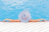 Women with big hat in pool. Photo by Anna Demianenko