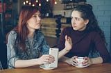 Two women sitting next to each other in a cafe