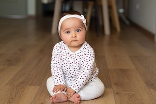 A female baby wearing a white outfit with red dots.
