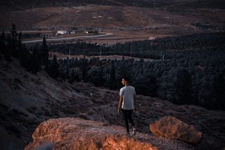 Man walking in a field with a storm brewing.