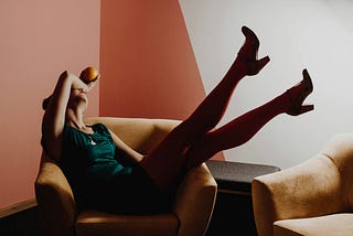 a woman laying back in a chair with her feet in the air.