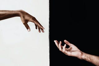 Two arms reaching out to each other. One arm has a white background, while the other has a black background.