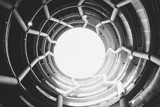 Black spiral staircase with white round ceiling. Courtesy of Nathan Thomassin (@vegatones) on Unsplash.com