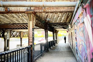 Person walking under rail bridge in Toronto’s Junction neighbourhood.