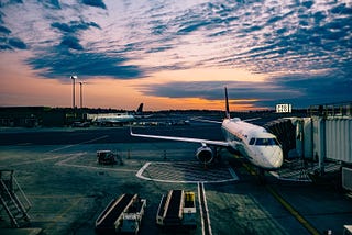 An airport apron on a summer’s evening, with a aircraft connected to a jet bridge