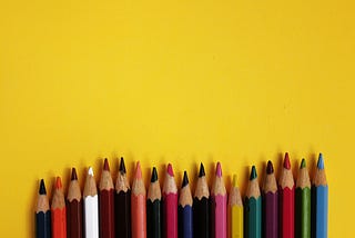 Variety of colored pencils on a yellow background