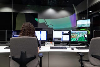 Person sitting in front of multiple computer monitors with keyboard