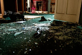 The floor of a home, covered in broken glass.