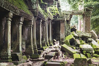 A photo of ancient ruins being enveloped by foliage and time