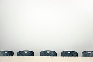 An empty board room table with chairs around it