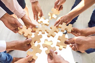 Company employees putting pieces of a jigsaw puzzle together