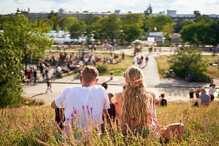 Couple sits in the grass together above the town.
