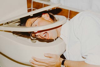 Photo of man throwing up in toilet.