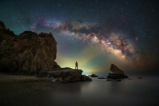 Someone stands against the background of the cosmos at night