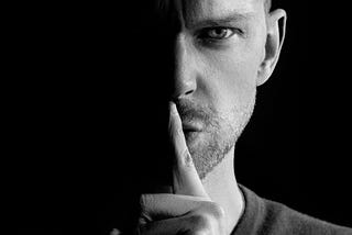 a man holding his finger to his lips, signalling silence