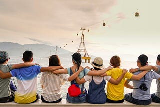 A group of children with arms around each other sitting on a dock