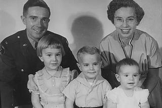 Photograph of the author’s family when he was two years old, with him and his sisters sitting in front of their smiling parents.