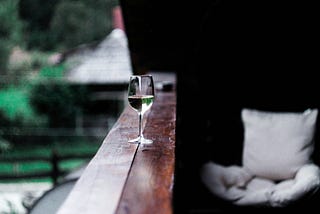 Glass of white wine on porch railing