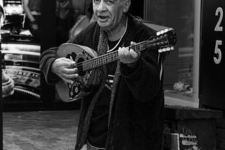 an old man playing his bouzouki