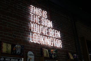 A Neon light on the wall says: This is the sign you’ve been looking for