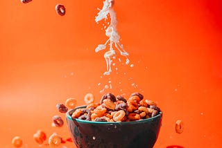 Milk pours from above into a small bowl of colorful Cheerios. A new analysis suggests that replacing even a small amount of ultra-processed foods (with an equal amount of minimally-processed ones) appears to drop cancer risk.