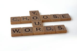 Scrabble letters arranged to spell “Choose Your Words”