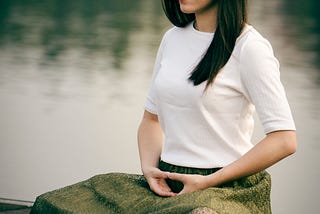Women meditating by a lake