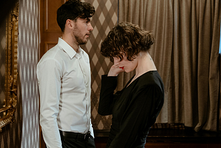 A photo of a man in a white shirt standing in front of a woman wearing a black dress.
