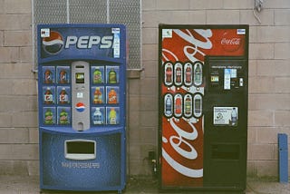 A Pepsi vending machine sits next to a Coke vending machine