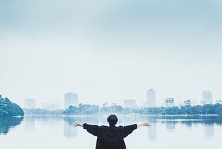 Woman looking across a lake at a skyline.