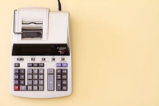 An adding machine sits on a yellow background