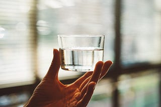 A hand holding up a glass of water.