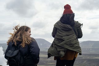 Two Women on a hike, looking over hilly terrain.