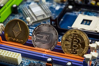 An Ethereum, Dash, and Bitcoin coin up against a motherboard